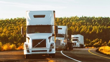 three 18-wheeler trucks driving